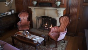Here is one area that our guests can sit and enjoy themselves at our durham nh area hotel. This image shows two comfy victorian style chairs in front of a fireplace. The fireplace is operating.