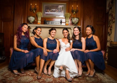 Here is a bridal party that coordinated their event with us at our seacoast nh hotel. The bride and bridal party are sitting on an aged red victorian couch. The bridesmaids are in blue dresses.