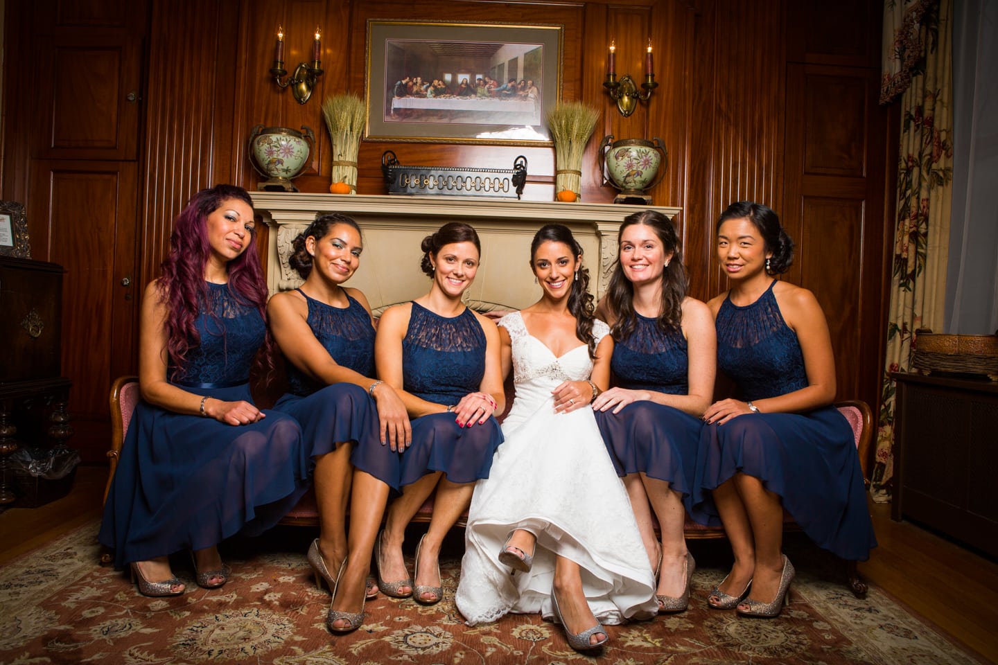 Here is a bridal party that coordinated their event with us at our seacoast nh hotel. The bride and bridal party are sitting on an aged red victorian couch. The bridesmaids are in blue dresses.