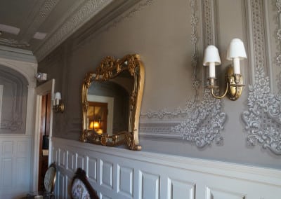 Here is a view of the beautiful victorian moldings on our wall in our durham nh hotel. There is a large gold mirror on the wall in between two golf wall lamps.