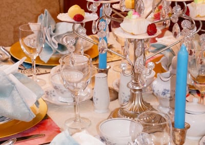 Here is a image of a tea room table dresssed with a three tier setting of deserts, place settings ready for guests and blue candles. Our tea room, unlike other durham NH area hotels, offers tea room experience.