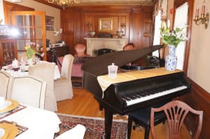 Here is another view of our tea room at our portsmouth nh area hotel. There is a table ready to seat four guests, a fireplace, and a piano.