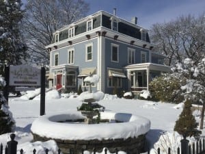 Wintertime view of our hotel seacoast nh. This is from the side of the inn, showing a snow covered water fountain and the sign for Silver Fountain Inn & tea parlor.