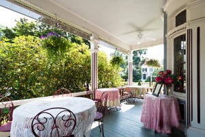 Here is the beautiful covered porch at our hotel durham nh. This shows three tables ready to invite guests to sit, relax, and enjoy great food.