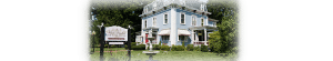This is the right side view of our Dover Nh hotel. The building is a pale blue with a red door. The sign displays Silver Fountain inn and tea parlor. There is a working water fountain next to the sign.