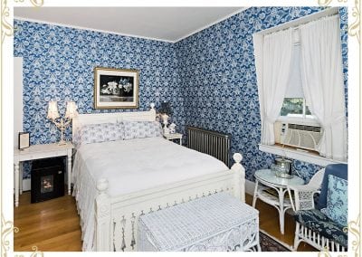 Check out this room at our Durham NH area hotel. This room is called the Eleanor. This is an image of the bed, wicker chairs, white tapestry, and blue victorian wall paper.