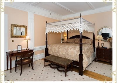 Here is the Chamber, a room at our Hotel in Dover NH. The image shows a bed, writing desk, night stand, and fresh flowers in a vase.