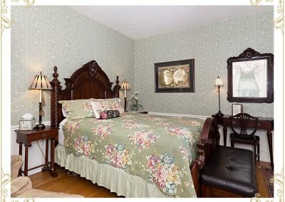 Check out the Duke, a popular room in our hotel in Durham NH. This image shows the bed with a dark wood headboard. There is an old map of the globe on the wall.