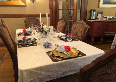 Here is an image showing a table set for six in our tea parlor. If you are looking for things to do on seacoast nh, this is a must visit. This table is set with golf plates and blue napkins.