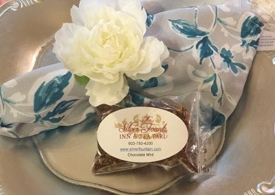 Here is a close up shot of one of the flavors of tea we serve. Looking for things to do in dover nh? Look no further than our tea parlor. This image shows a silver plate with a fresh flower tied around a napkin and a bag of loose leaf tea.